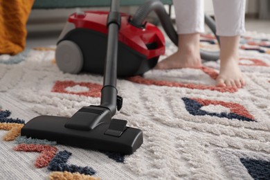 Woman cleaning carpet with vacuum cleaner at home, closeup. Space for text