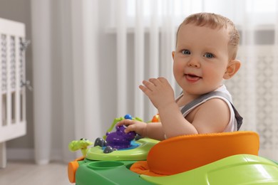 Photo of Portrait of cute baby with toy walker at home, space for text. Learning to walk