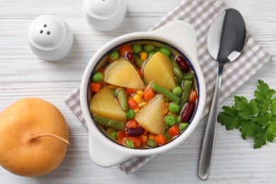 Photo of Bowl of delicious turnip soup served on white wooden table, flat lay