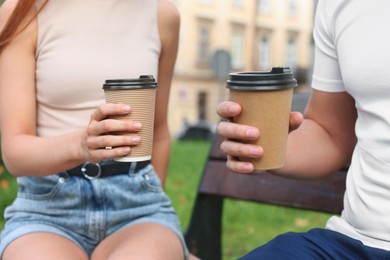 Coffee to go. Couple with paper cups outdoors, closeup