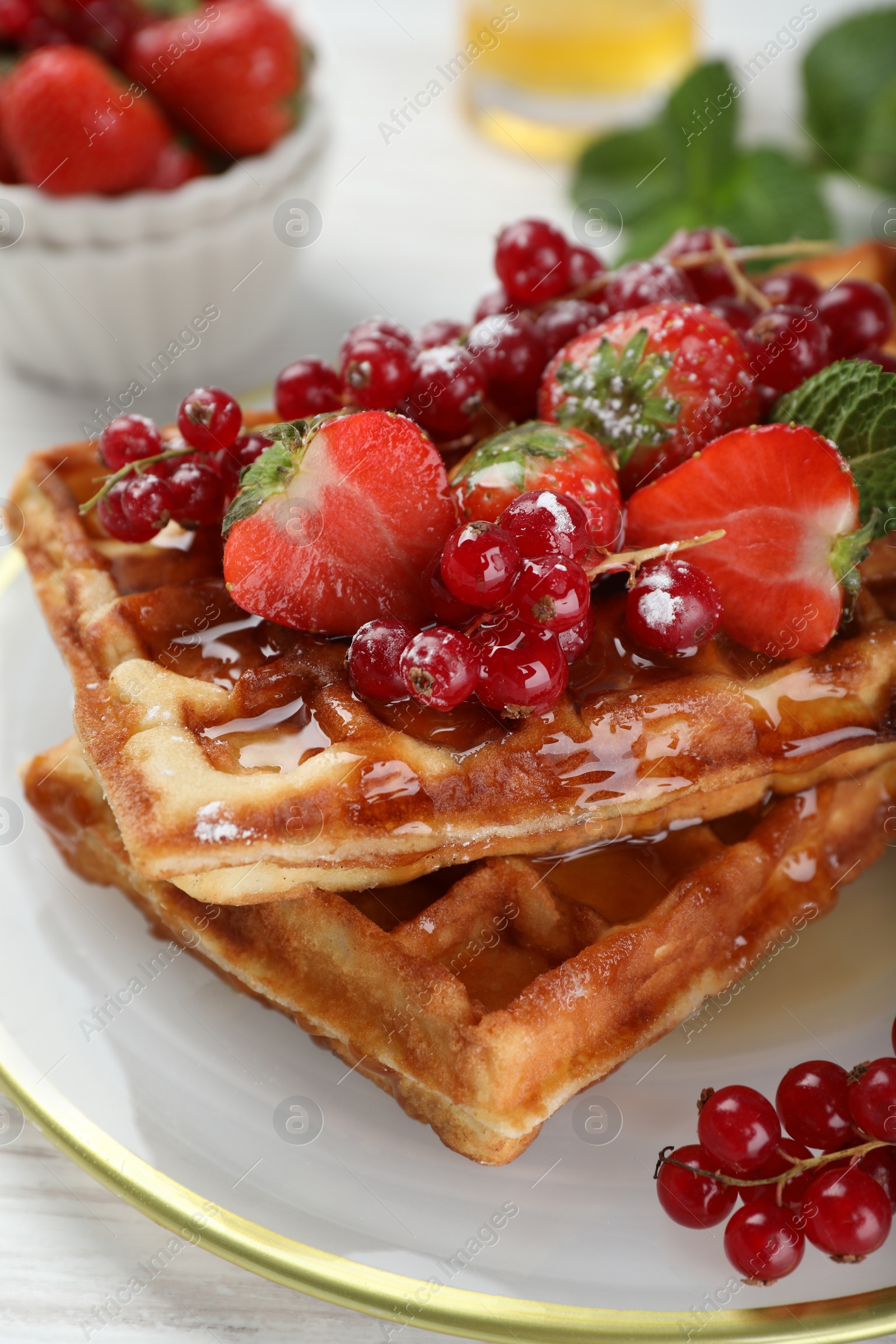 Photo of Plate of delicious Belgian waffles with berries and honey on table, closeup