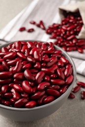 Photo of Raw red kidney beans in bowl on light grey table, closeup