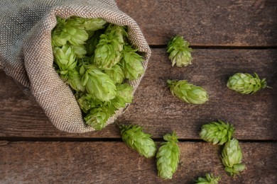 Photo of Sack and fresh green hops on wooden table, flat lay