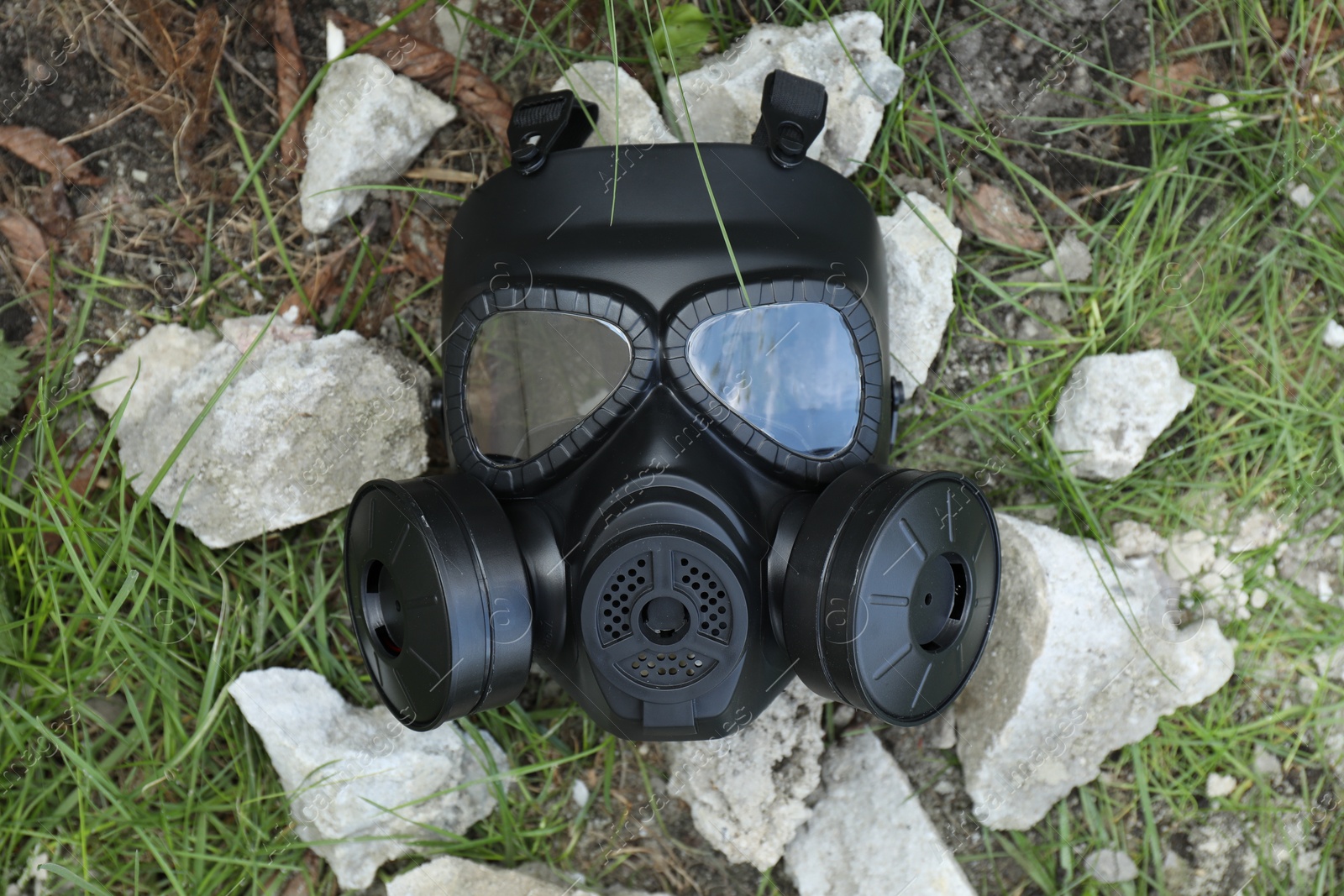 Photo of One gas mask on ground with stones outdoors, top view