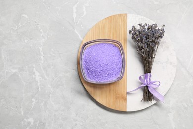 Photo of Violet sea salt in bowl and lavender flowers on grey marble table, top view. Space for text