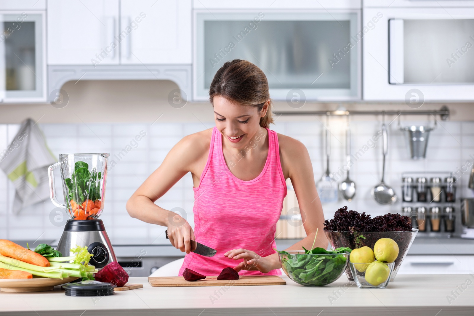 Photo of Young woman preparing tasty healthy smoothie at table in kitchen