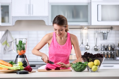 Young woman preparing tasty healthy smoothie at table in kitchen