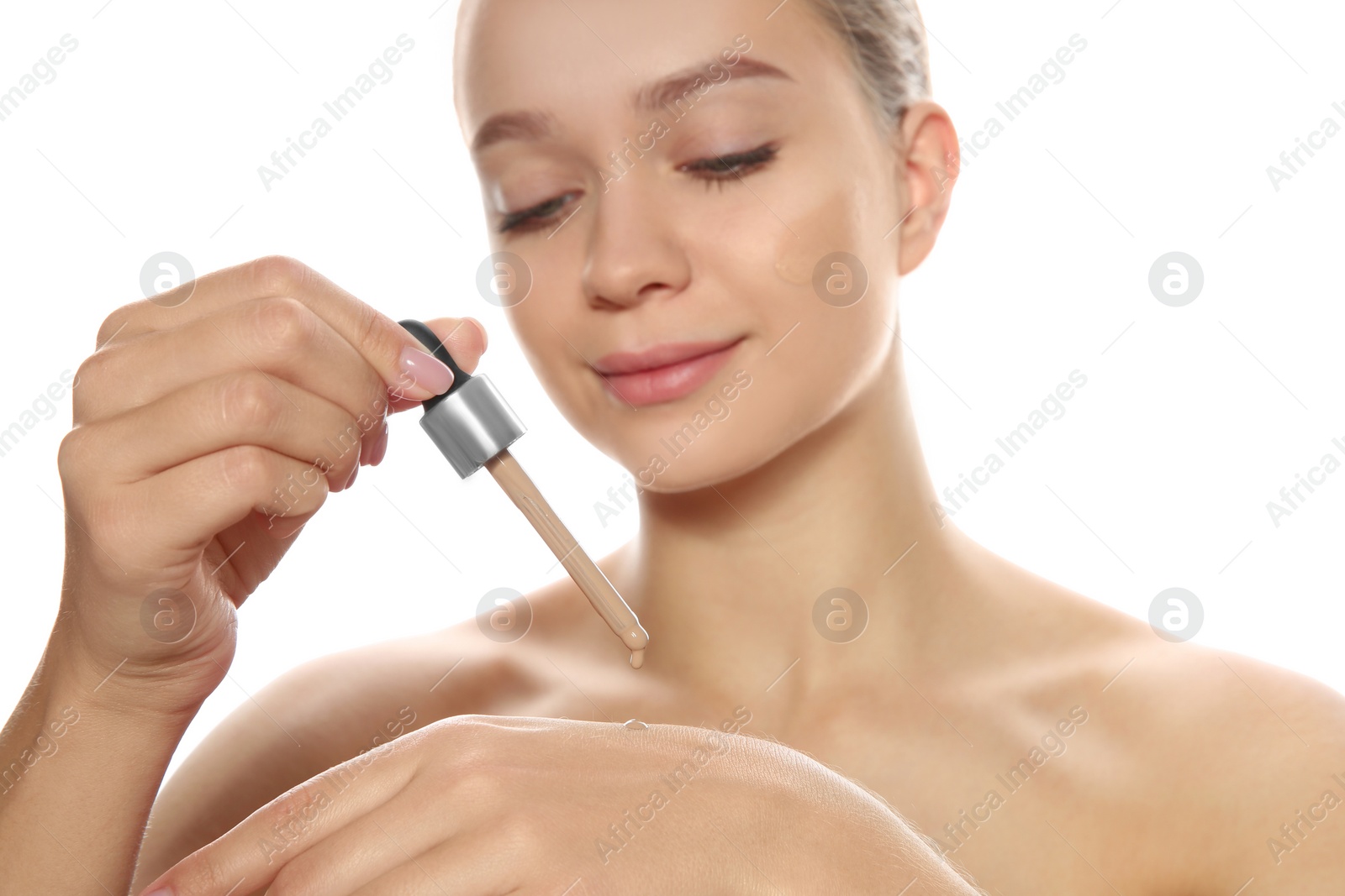 Photo of Young woman testing liquid foundation on her hand against white background