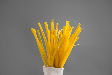 Uncooked noodles on grey background, closeup. Italian pasta