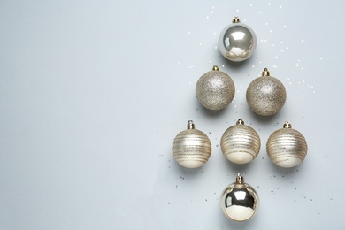Photo of Christmas tree shape made of decorative balls on light background, flat lay. Space for text