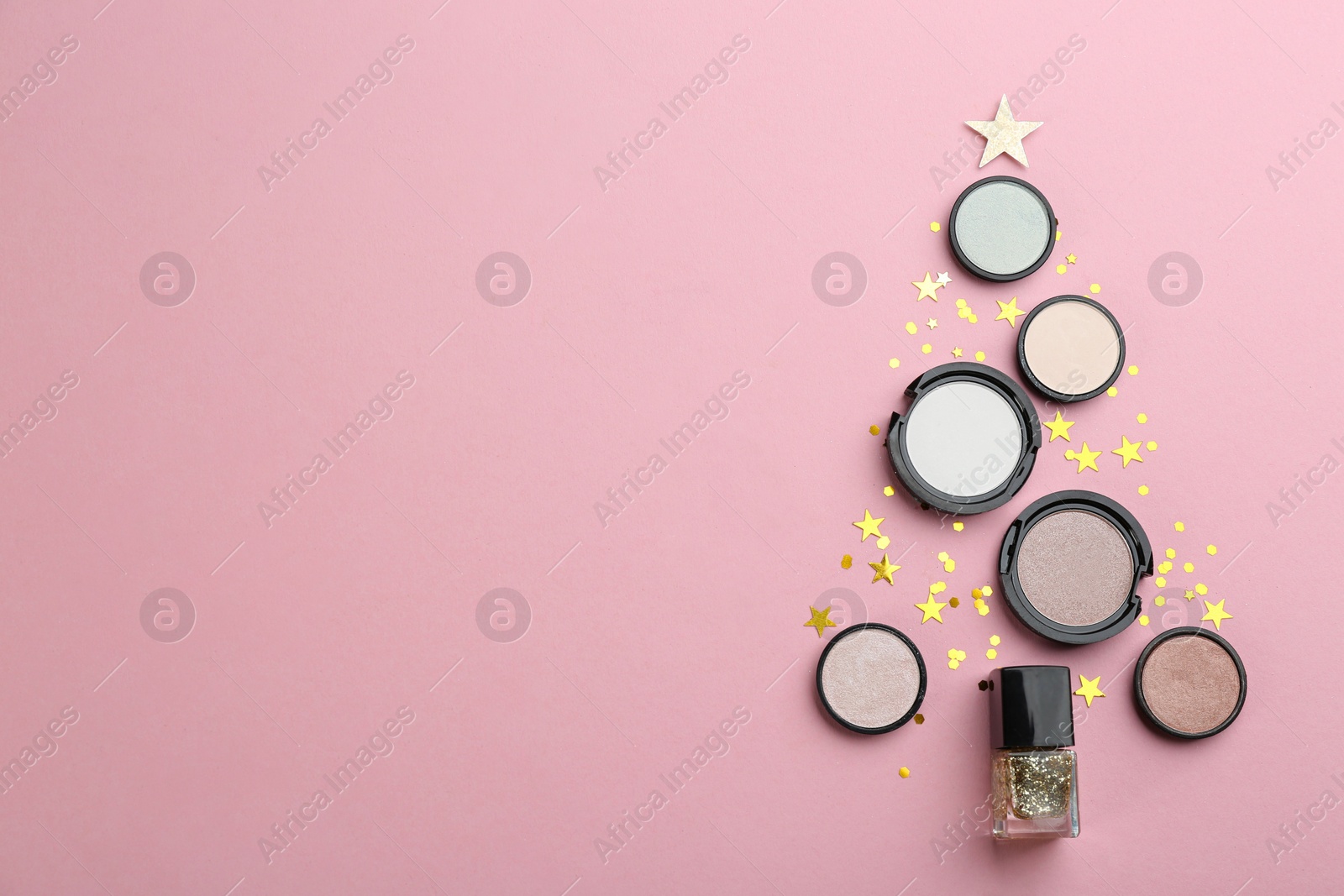 Photo of Christmas tree shape of decorative cosmetic products on pink background, flat lay with space for text. Winter care