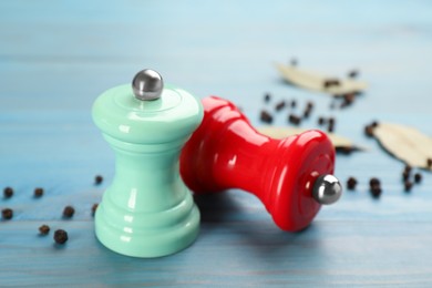 Photo of Salt and pepper shakers on turquoise wooden table, closeup. Spice mill