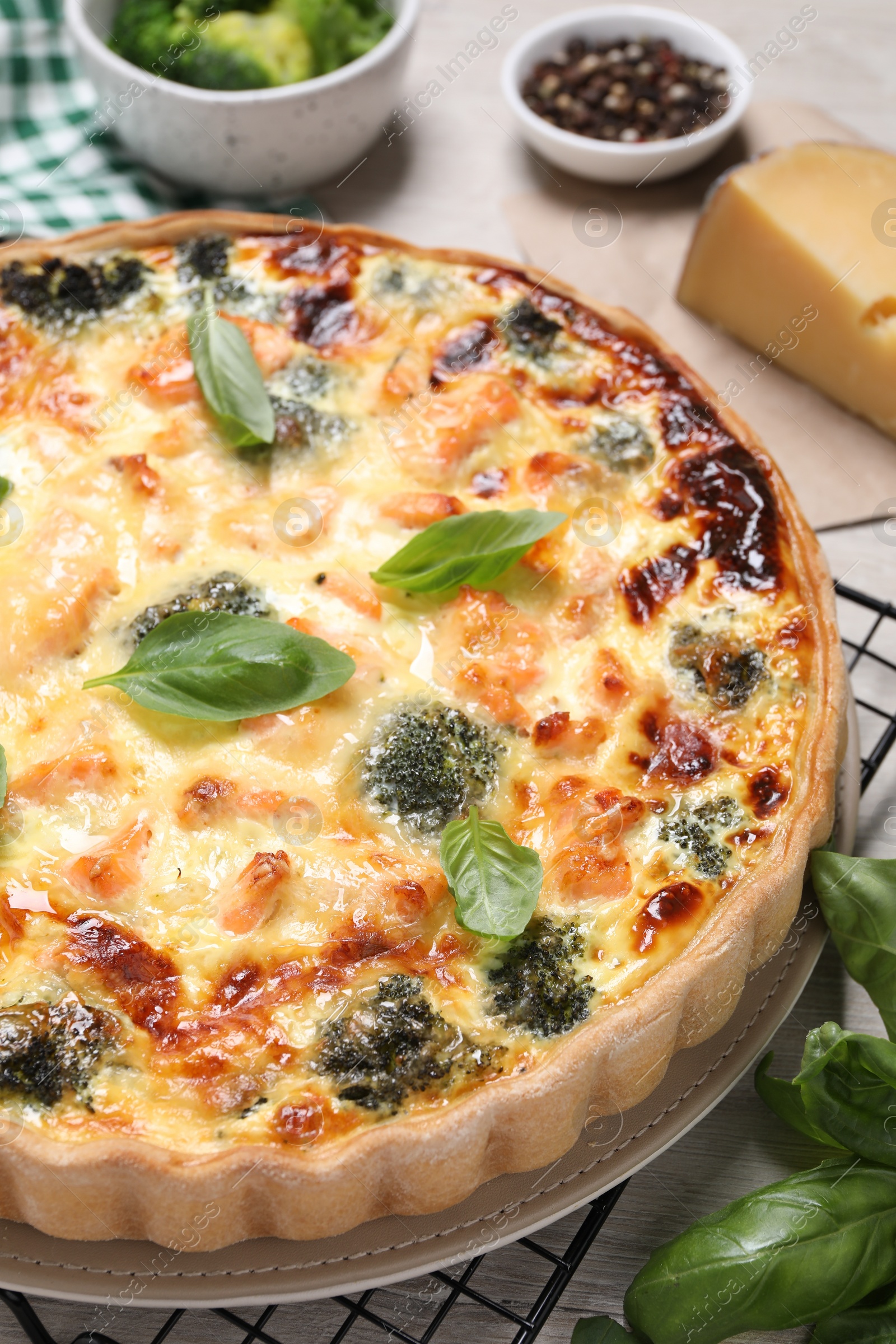 Photo of Delicious homemade quiche with salmon, broccoli and basil leaves on table