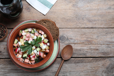 Photo of Delicious cold okroshka with kvass served on wooden table, flat lay and space for text. Traditional Russian summer soup