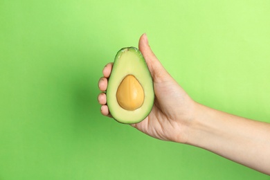 Photo of Woman holding ripe cut avocado on color background