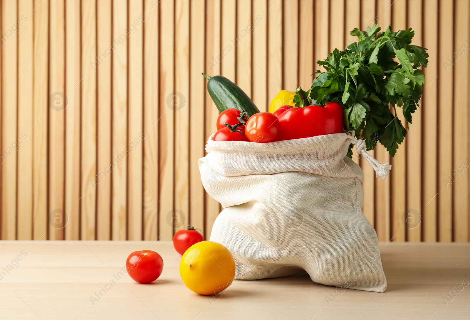 Photo of Cotton eco bag with vegetables and fruits on wooden table. Space for text