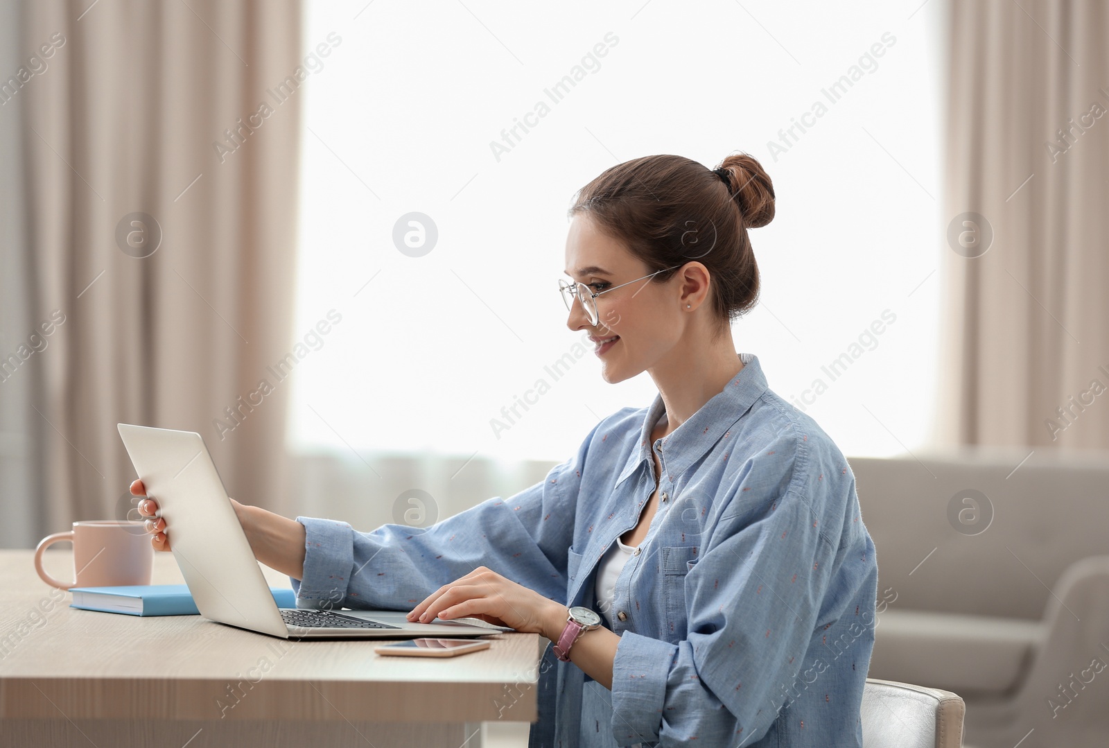 Image of Young woman working on laptop at home