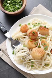 Photo of Delicious scallop pasta with green onion served on grey table, top view