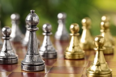 Photo of Silver bishop and other chess pieces on game board against blurred background, closeup
