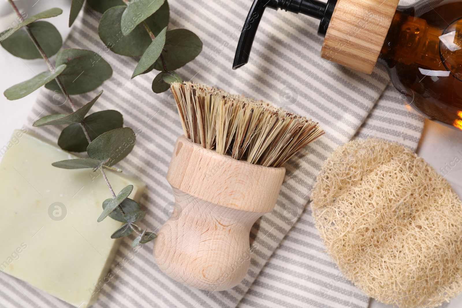 Photo of Cleaning brush, sponge, dispenser, soap bar and eucalyptus leaves on table, top view