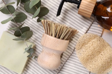 Photo of Cleaning brush, sponge, dispenser, soap bar and eucalyptus leaves on table, top view