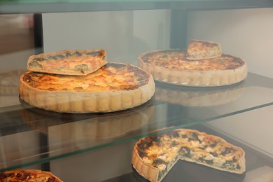 Different delicious quiches on counter in store
