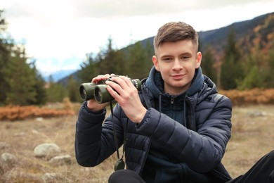 Photo of Boy looking through binoculars in beautiful mountains