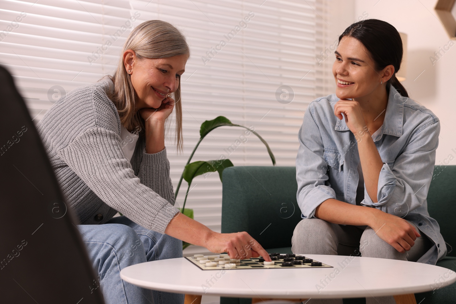 Photo of Women playing checkers at coffee table in room