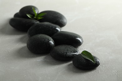 Photo of Spa stones with water drops and green leaves on light table