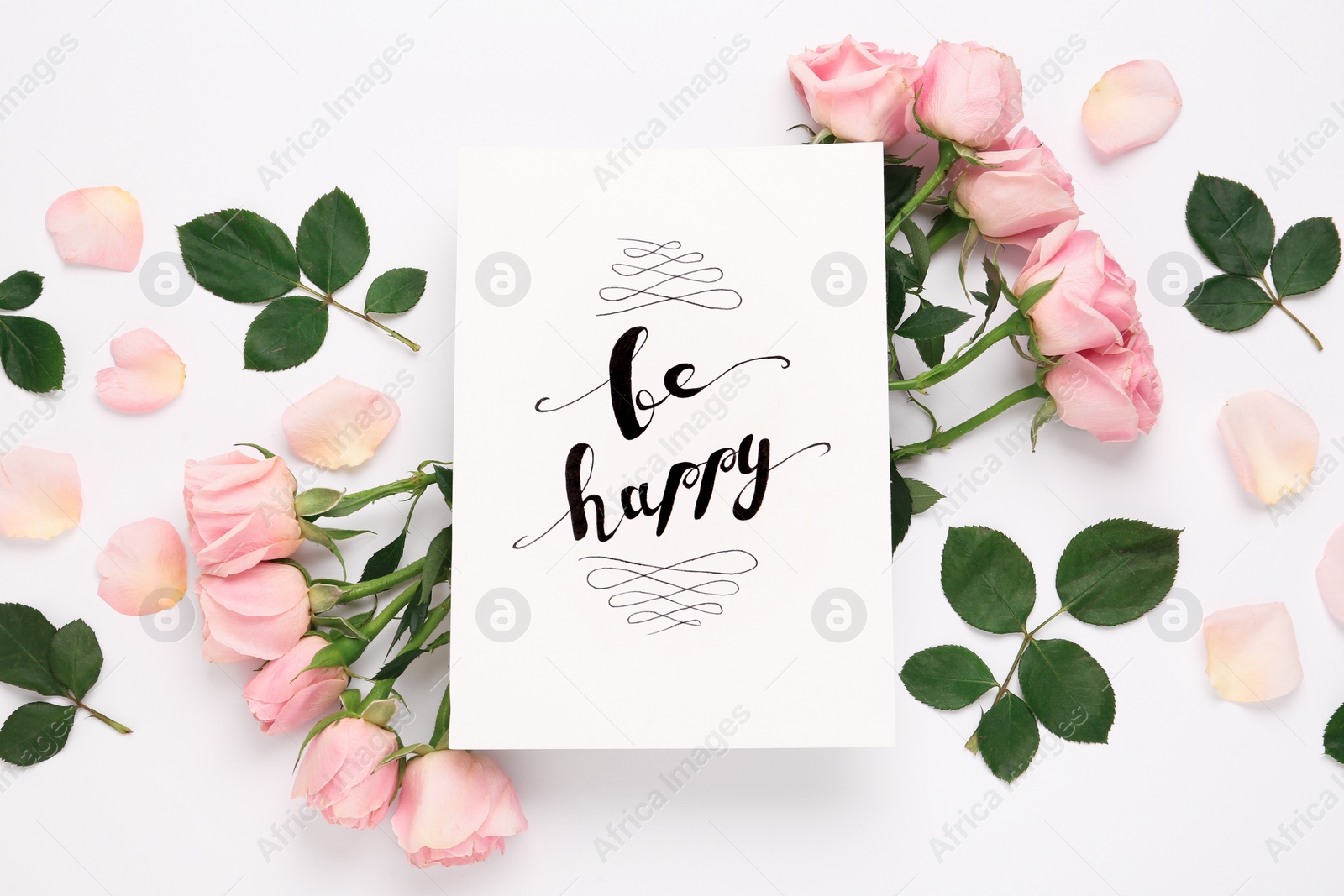 Photo of Frame of beautiful flowers and paper card with handwritten text Be happy on white background, flat lay