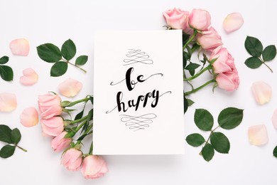 Frame of beautiful flowers and paper card with handwritten text Be happy on white background, flat lay