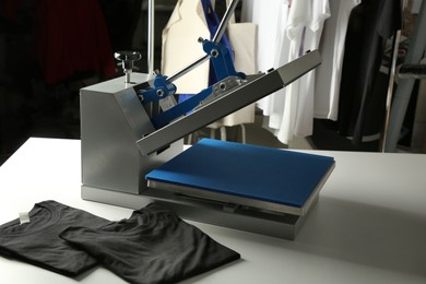 Photo of Printing logo. Heat press and black t-shirt on white table