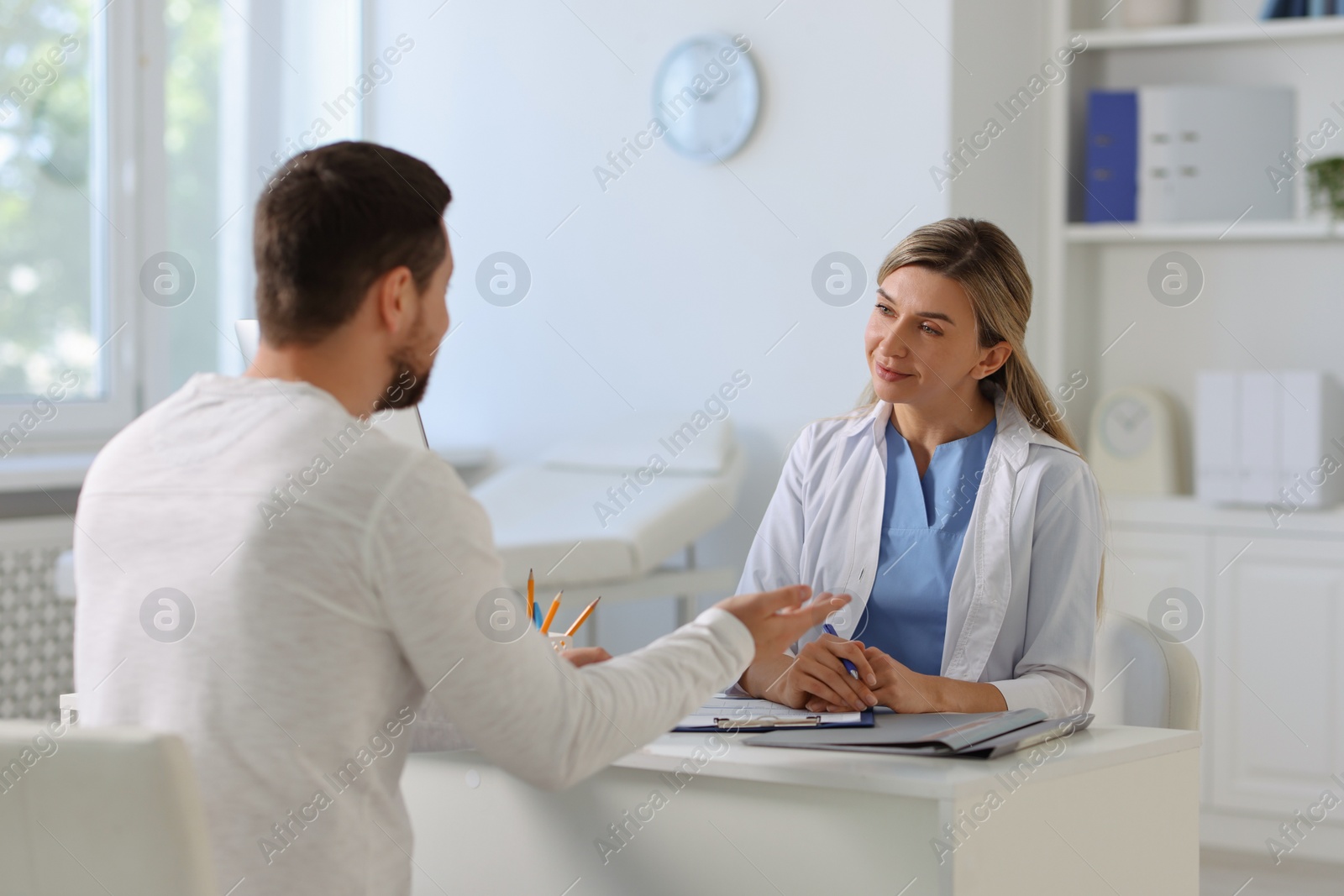 Photo of Professional doctor working with patient at white table in hospital