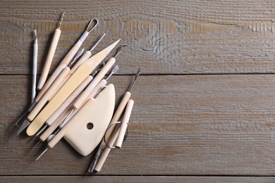 Set of different clay crafting tools on wooden table, top view. Space for text