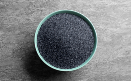 Photo of Poppy seeds in bowl on grey table, top view