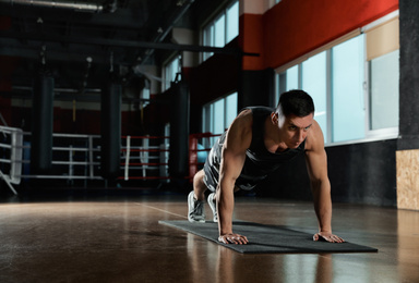 Photo of Man doing plank exercise in modern gym