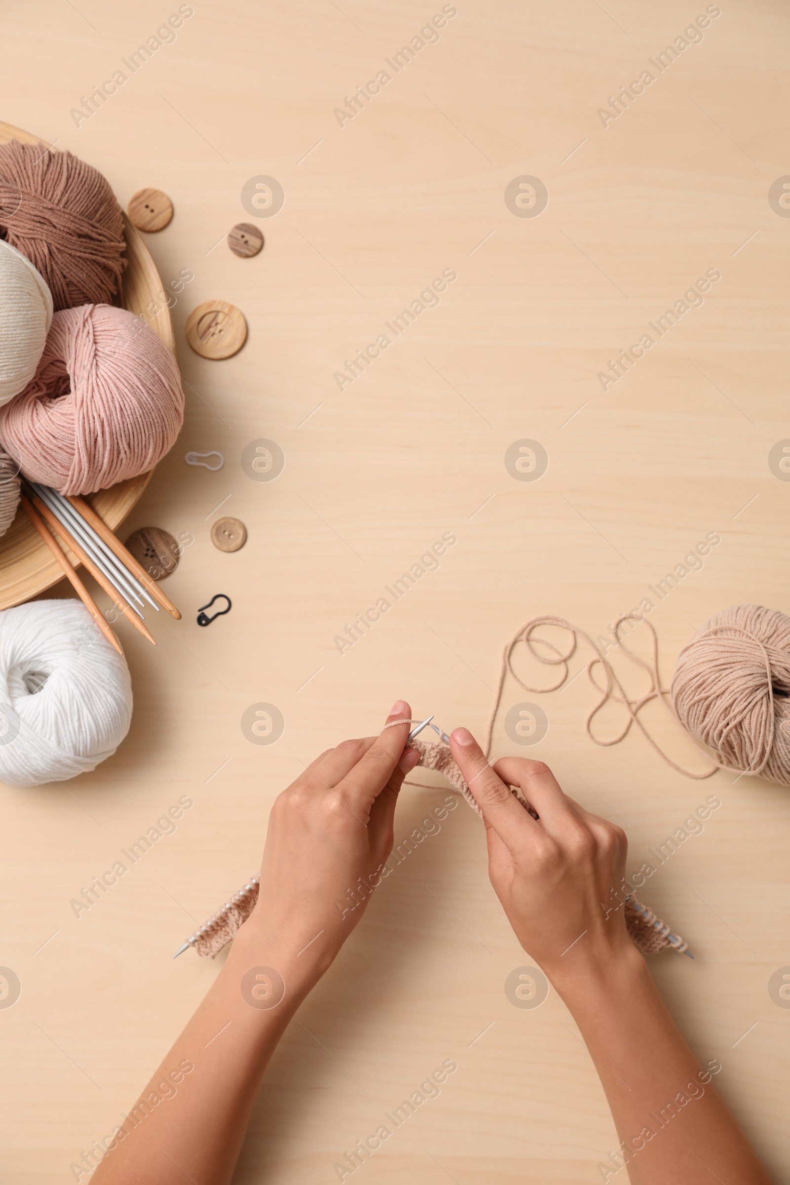 Photo of Woman knitting with threads at wooden table, top view. Engaging hobby