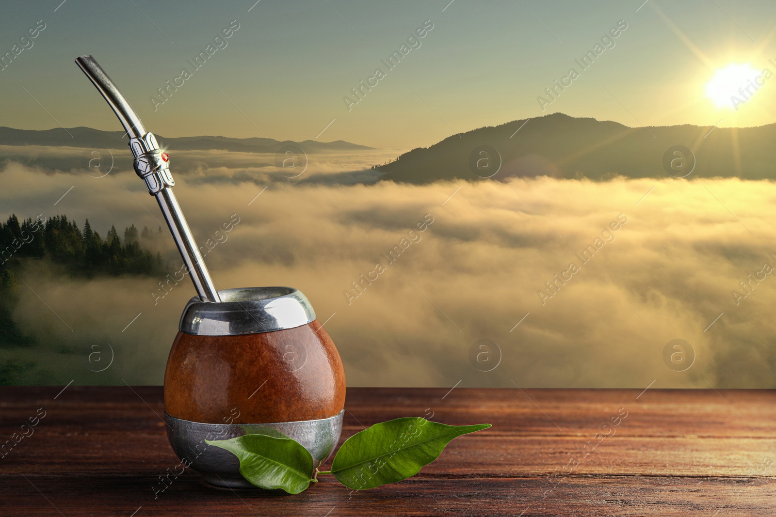 Image of Calabash with mate tea and bombilla on wooden table and beautiful view of mountain landscape, space for text