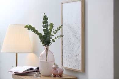 Vase with fresh eucalyptus branches on table in room. Interior design