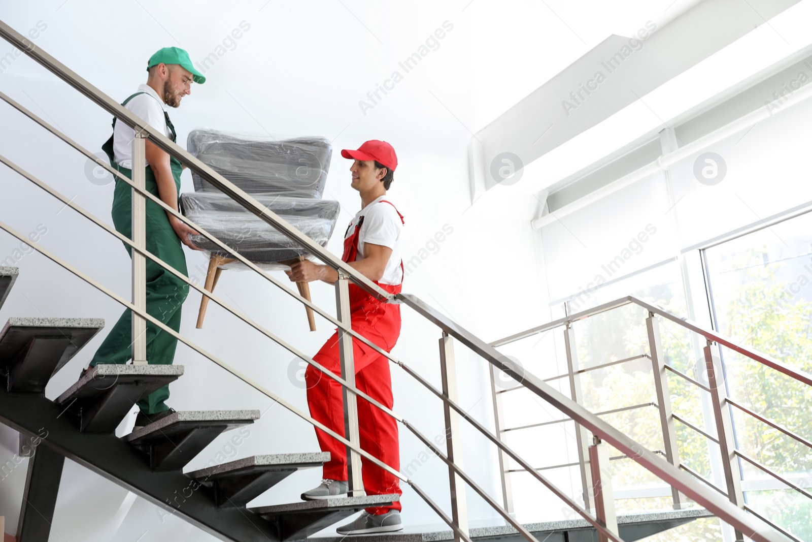 Photo of Male movers carrying armchair in new house