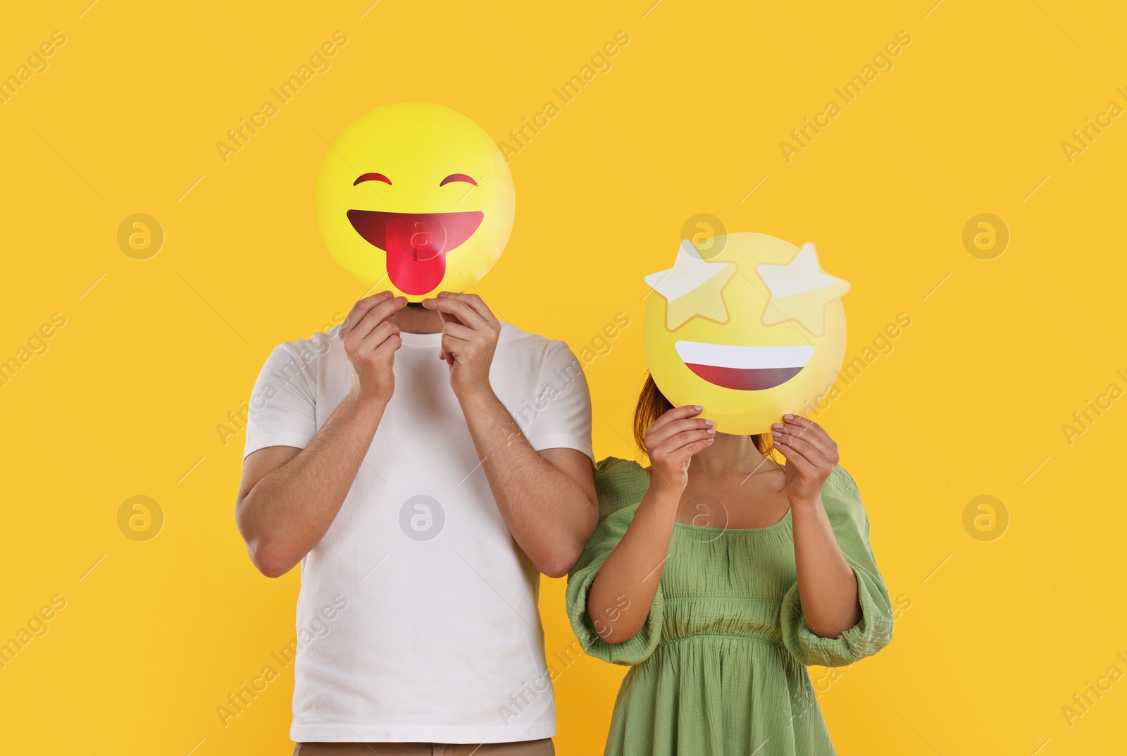 Photo of People covering faces with emoticons on yellow background