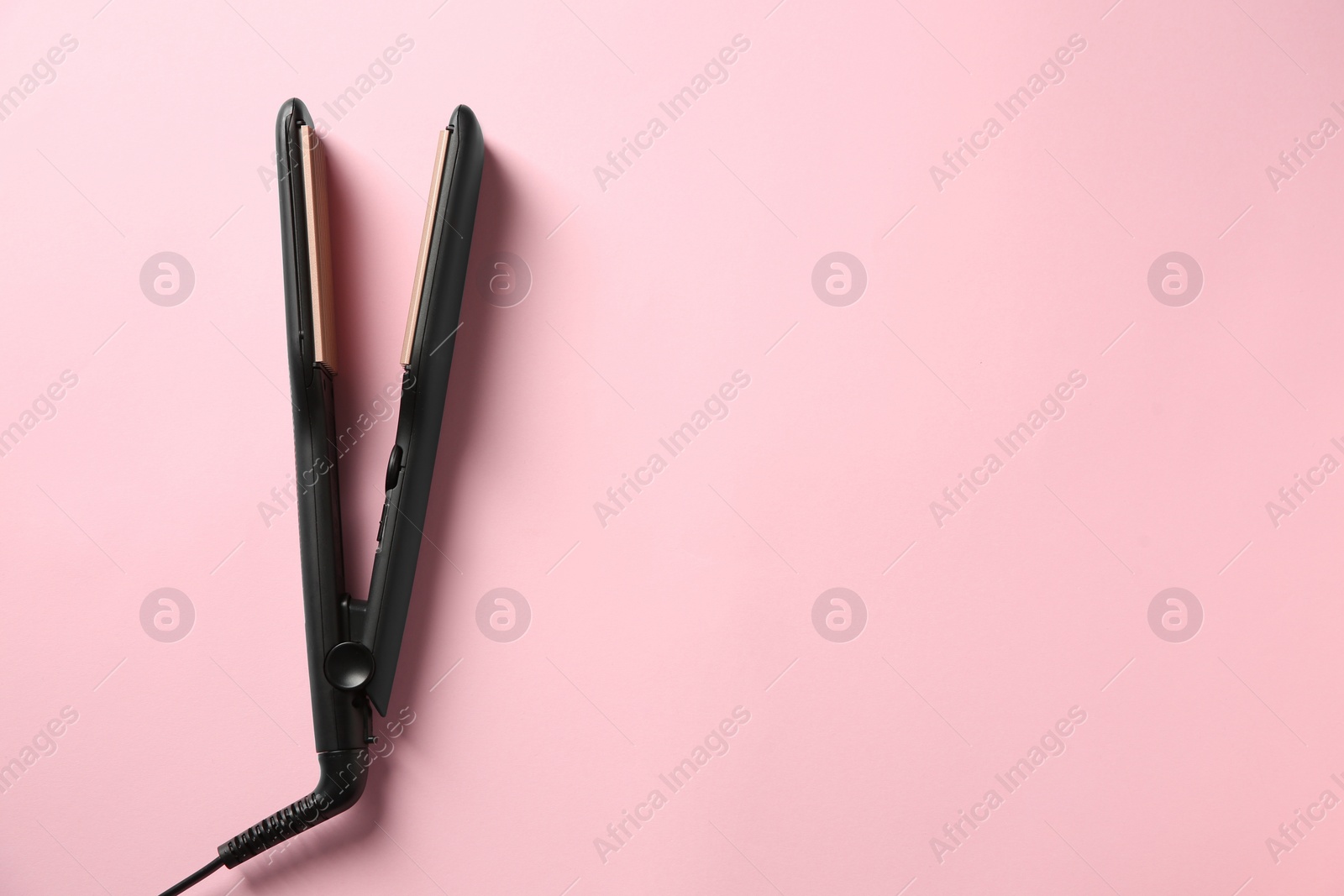 Photo of Modern flat hair iron on pink background, top view. Space for text