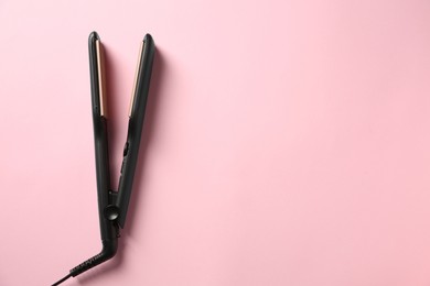 Photo of Modern flat hair iron on pink background, top view. Space for text