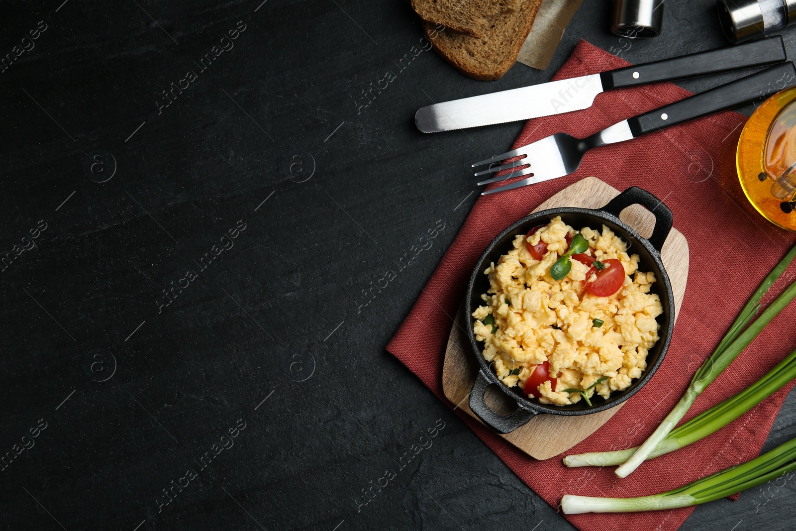 Photo of Tasty scrambled eggs served on black table, flat lay. Space for text