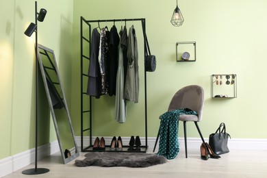 Photo of Modern dressing room interior with clothing rack, chair and mirror