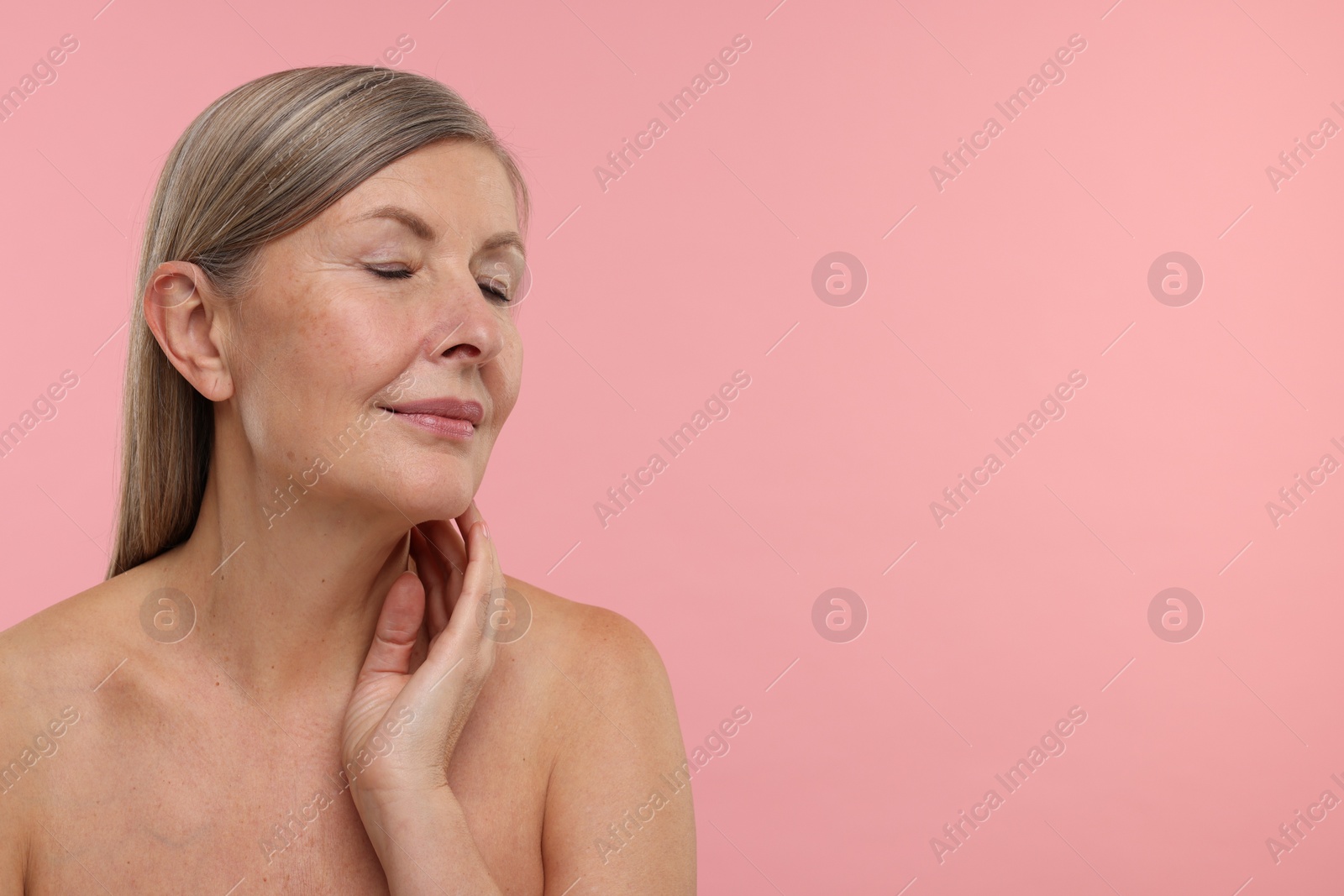 Photo of Beautiful woman touching her neck on pink background, space for text