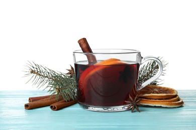 Photo of Composition with glass cup of mulled wine, cinnamon, orange and fir branch on table against white background