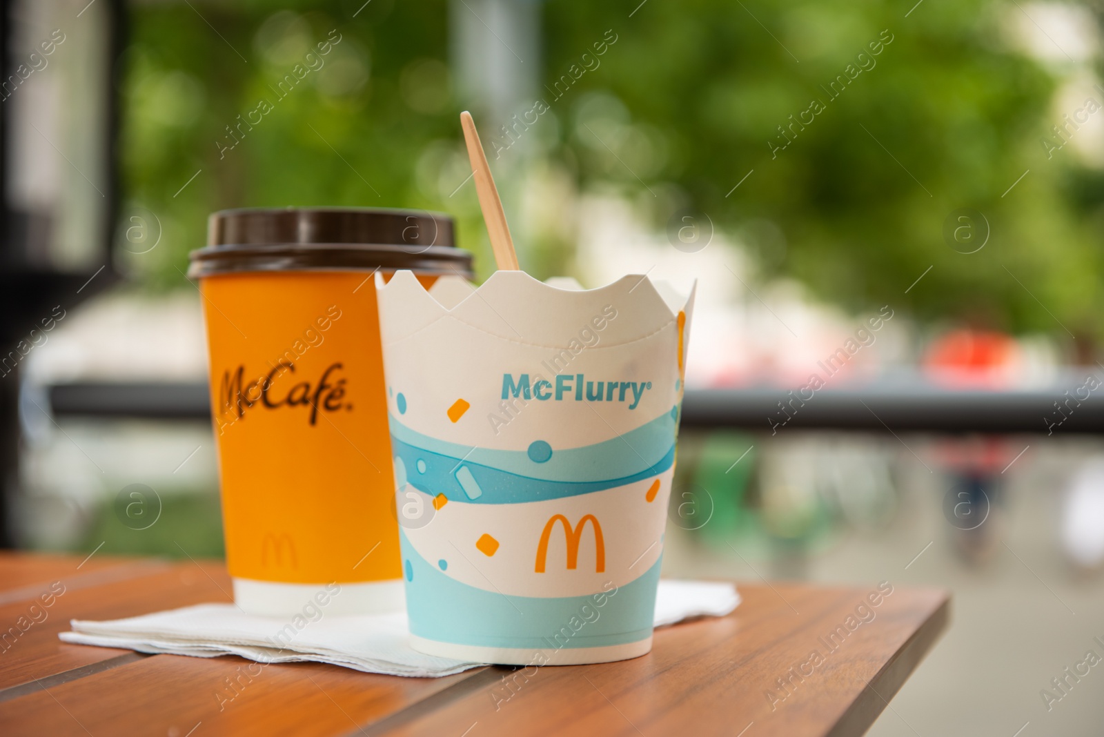 Photo of WARSAW, POLAND - SEPTEMBER 04, 2022: McDonald's hot drink and ice cream on wooden table outdoors, space for text