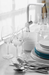 Photo of Different clean dishware, cutlery and glasses on countertop in kitchen