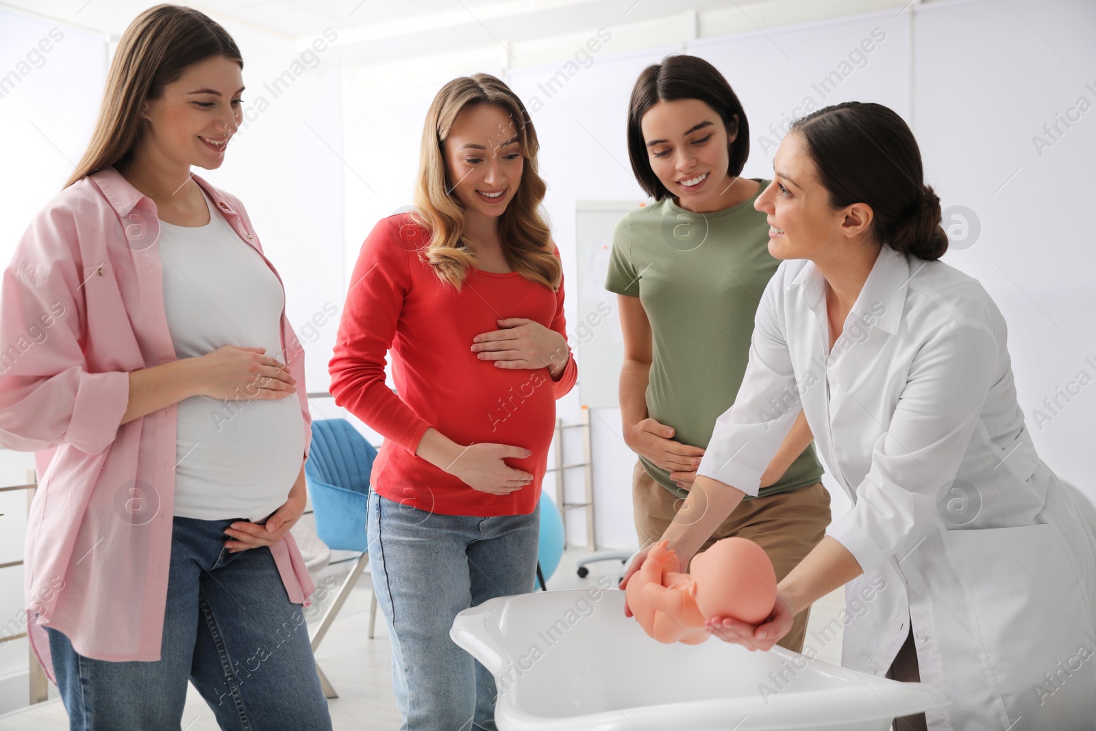 Photo of Pregnant women learning how to bathe baby at courses for expectant mothers indoors